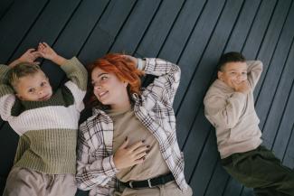 Woman lying down with two young boys next to her.